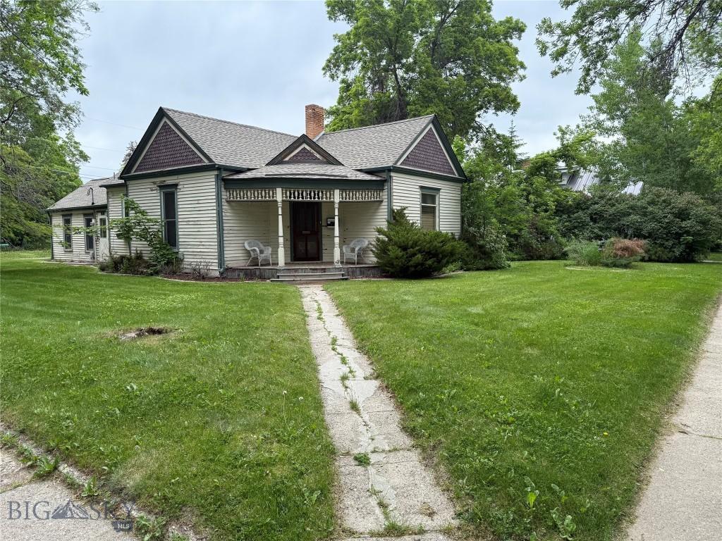 221 S 7th Ave, Bozeman, MT 59715 - view of front of home with a chimney, a front yard, a shingled roof, and covered porch