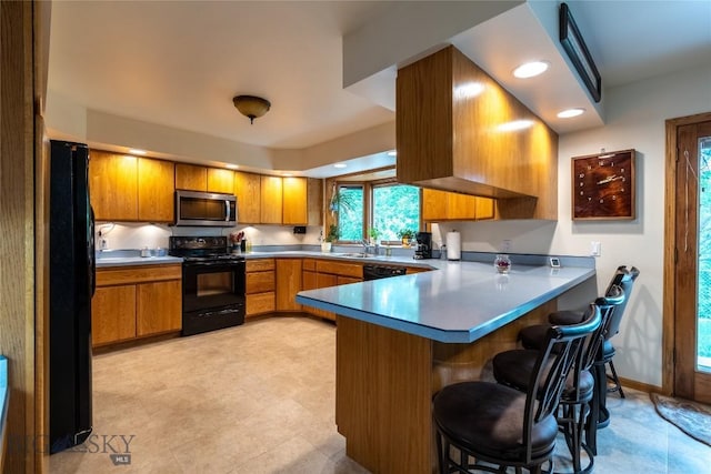 400 E 9th Ave, Big Timber, MT 59011 - kitchen with black appliances, a peninsula, brown cabinets, a breakfast bar area, and recessed lighting