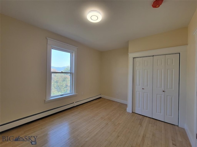 1043 W Galena St, Butte, MT 59701 - unfurnished bedroom featuring light wood-type flooring, a baseboard radiator, and a closet