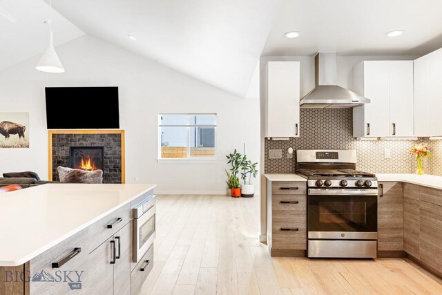 1991 Ryun Sun Way, Bozeman, MT 59718 - kitchen featuring stainless steel appliances, wall chimney exhaust hood, light countertops, light wood-type flooring, and open floor plan
