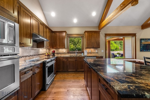 2497 Northview, Bozeman, MT 59715 - kitchen featuring appliances with stainless steel finishes, vaulted ceiling, healthy amount of natural light, under cabinet range hood, and tasteful backsplash