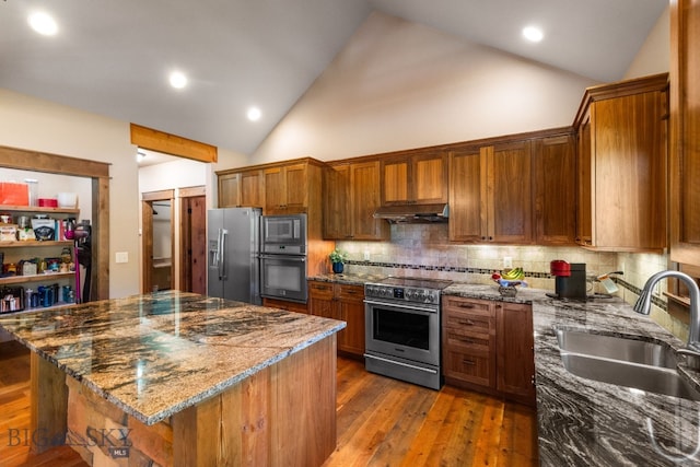 2497 Northview, Bozeman, MT 59715 - kitchen with appliances with stainless steel finishes, under cabinet range hood, a center island, dark stone countertops, and backsplash