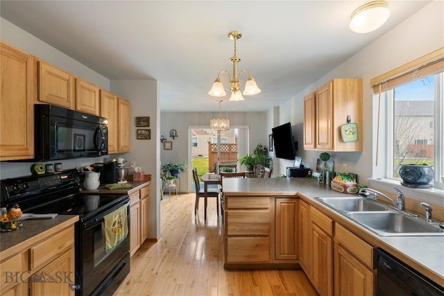 1030 N River Rock St, Belgrade, MT 59714 - kitchen with black appliances, a chandelier, light wood-style flooring, pendant lighting, and a peninsula