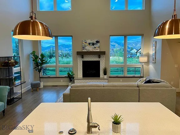 1792 Windrow Dr, Bozeman, MT 59718 - living area featuring wood finished floors, a towering ceiling, healthy amount of natural light, and a fireplace with raised hearth