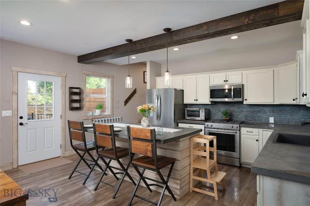 219 W Adams, Three Forks, MT 59752 - kitchen featuring stainless steel appliances, dark countertops, beamed ceiling, tasteful backsplash, and dark wood finished floors