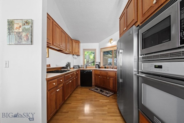 8A Gallatin Dr, Bozeman, MT 59718 - kitchen with stainless steel appliances, light wood-type flooring, light countertops, brown cabinets, and a textured ceiling