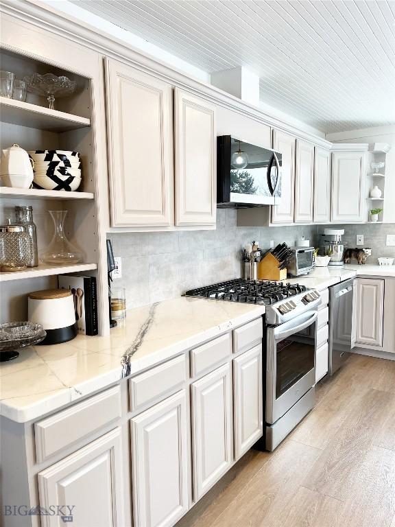 3575 Stucky Rd, Bozeman, MT 59715 - kitchen with stainless steel appliances, open shelves, light wood-type flooring, and white cabinets