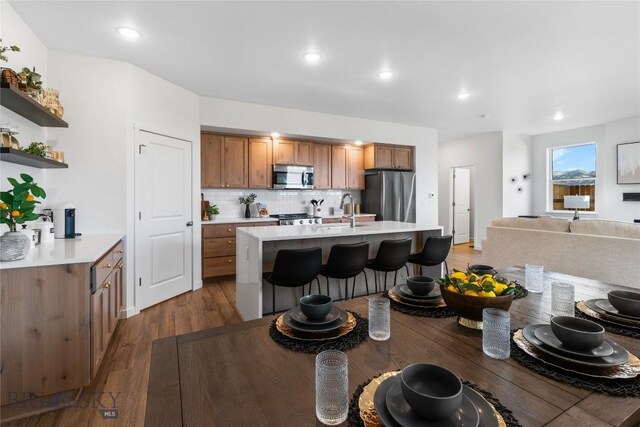608 Mira Way Unit A, Belgrade, MT 59714 - kitchen featuring appliances with stainless steel finishes, brown cabinets, a breakfast bar, light countertops, and recessed lighting