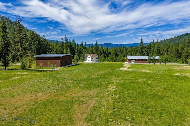 189 Blue Creek Rd, Heron, MT 59844 - view of green lawn with a forest view, an outbuilding, and a mountain view