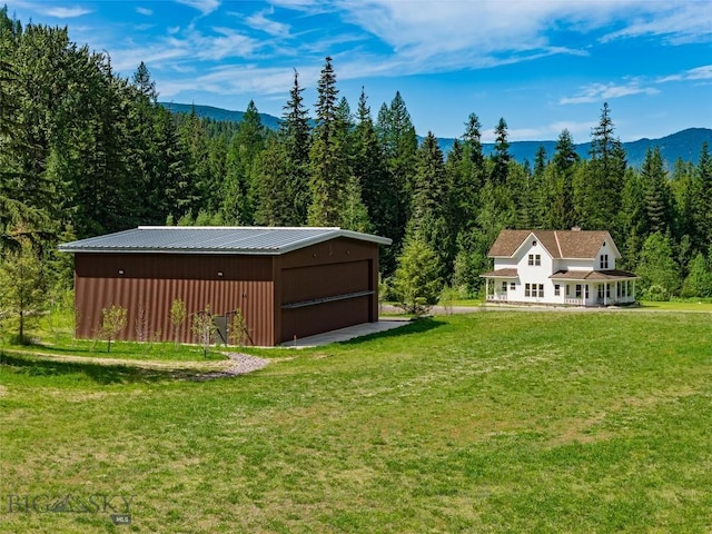 189 Blue Creek Rd, Heron, MT 59844 - view of grassy yard featuring a forest view, an outdoor structure, a garage, and a mountain view