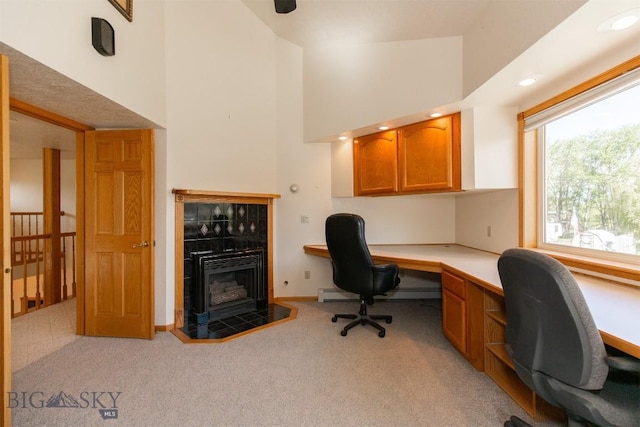 507 E Poppleton, Sheridan, MT 59749 - home office with built in study area, a high ceiling, light colored carpet, a baseboard heating unit, and a tile fireplace