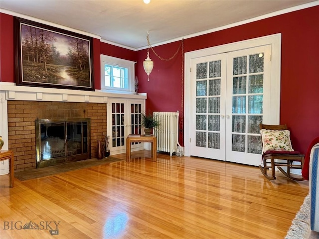 108 S 8th St, Livingston, MT 59047 - unfurnished living room featuring french doors, radiator, ornamental molding, wood finished floors, and a fireplace