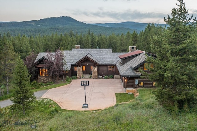 2055 Ousel Falls Rd, Big Sky, MT 59716 - view of front facade featuring a forest view, a chimney, a mountain view, and concrete driveway