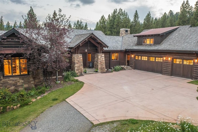 2055 Ousel Falls Rd, Big Sky, MT 59716 - log-style house with driveway, stone siding, an attached garage, and a chimney