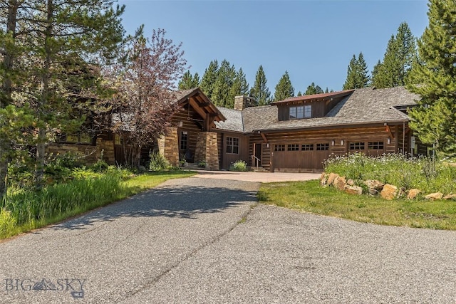 2055 Ousel Falls Rd, Big Sky, MT 59716 - log home featuring a chimney, a garage, driveway, stone siding, and log exterior
