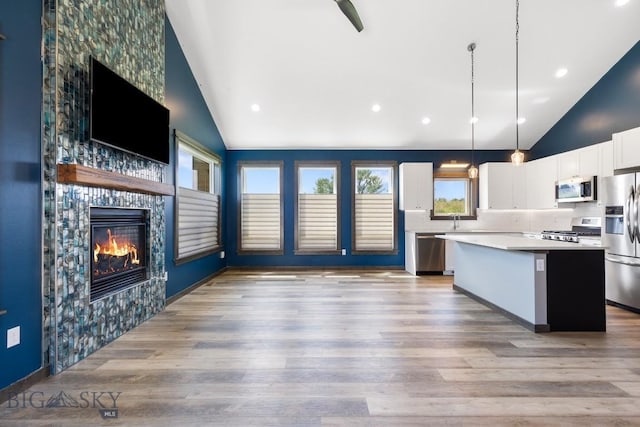 142 Albrey Trl Unit C, Bozeman, MT 59718 - kitchen with stainless steel appliances, vaulted ceiling, a fireplace, a center island, and white cabinets