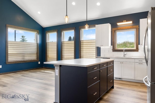142 Albrey Trl Unit C, Bozeman, MT 59718 - kitchen featuring vaulted ceiling, white cabinets, light countertops, a kitchen island, and freestanding refrigerator