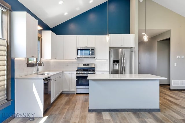 142 Albrey Trl Unit C, Bozeman, MT 59718 - kitchen featuring stainless steel appliances, light wood-style flooring, a kitchen island, light countertops, and high vaulted ceiling