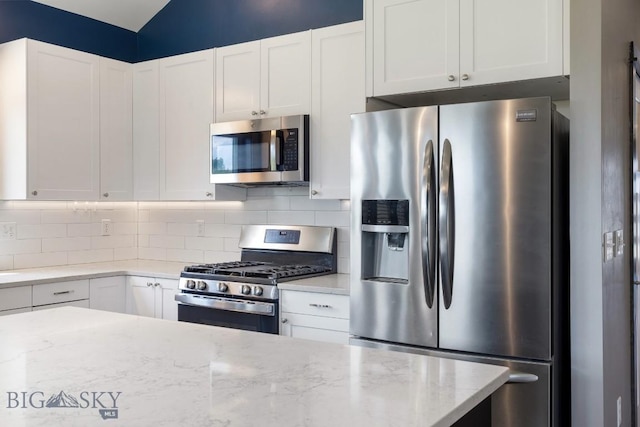 142 Albrey Trl Unit C, Bozeman, MT 59718 - kitchen with appliances with stainless steel finishes, tasteful backsplash, white cabinets, light stone counters, and vaulted ceiling