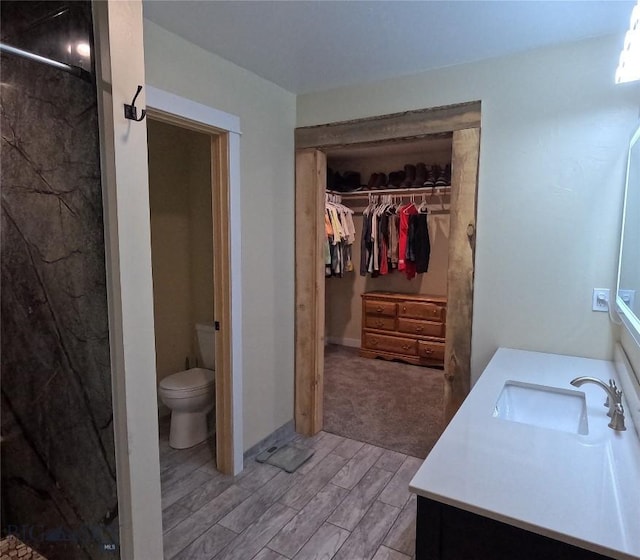 701 Barnett St, Dillon, MT 59725 - bathroom featuring vanity, a marble finish shower, a spacious closet, and wood finish floors