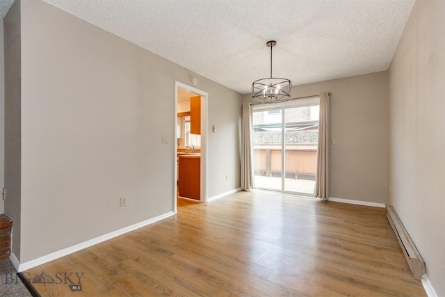 12 E Garfield St Unit D4, Bozeman, MT 59715 - unfurnished dining area featuring a baseboard radiator, a textured ceiling, wood finished floors, and a chandelier