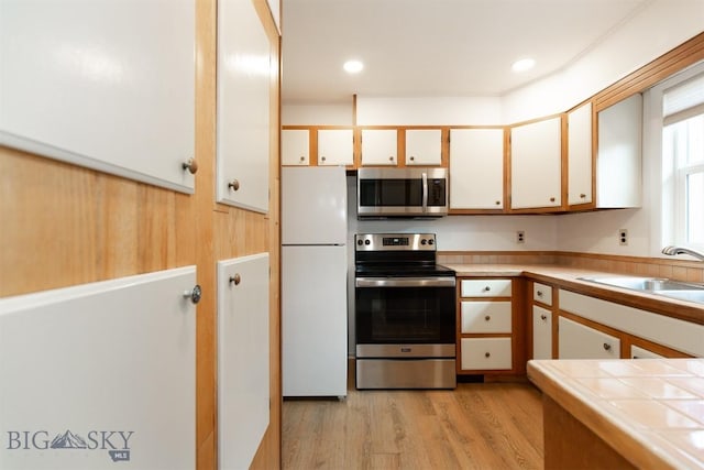 12 E Garfield St Unit D4, Bozeman, MT 59715 - kitchen with stainless steel appliances, light wood-type flooring, tile counters, and white cabinetry