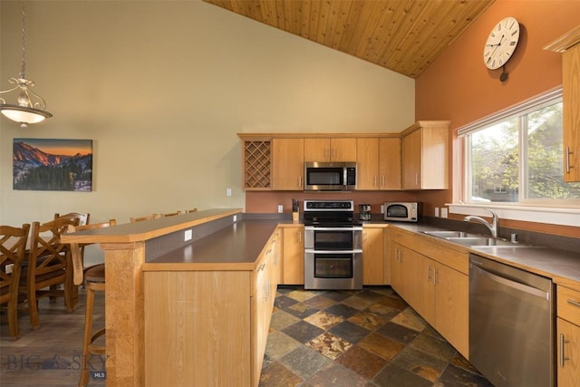456 Firelight, Big Sky, MT 59716 - kitchen featuring appliances with stainless steel finishes, a peninsula, high vaulted ceiling, light brown cabinets, and a breakfast bar