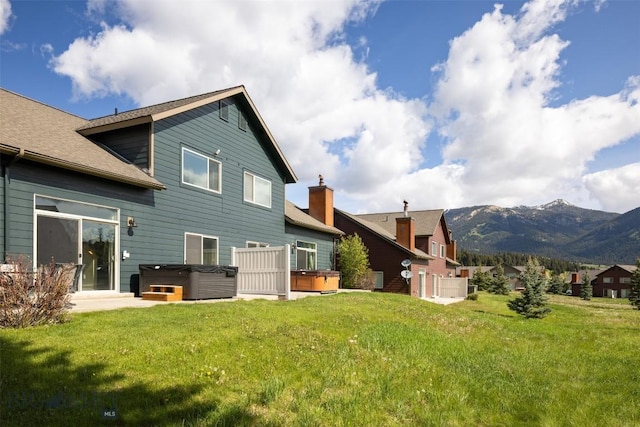 456 Firelight, Big Sky, MT 59716 - rear view of house featuring a hot tub, a mountain view, a yard, and a shingled roof