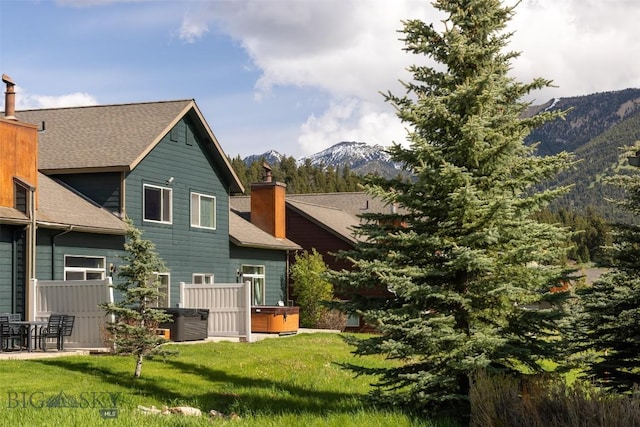 456 Firelight, Big Sky, MT 59716 - back of property featuring a chimney, a mountain view, a yard, and roof with shingles