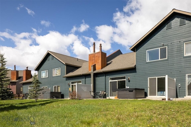 456 Firelight, Big Sky, MT 59716 - rear view of house with a hot tub, a chimney, a lawn, and roof with shingles