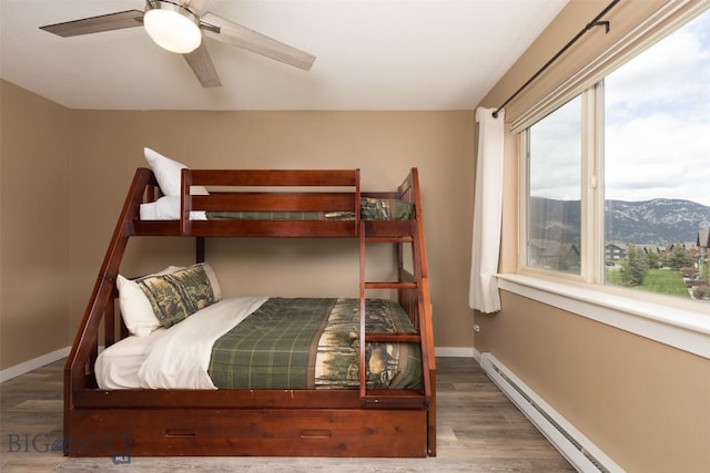 456 Firelight, Big Sky, MT 59716 - bedroom featuring a baseboard radiator, wood finished floors, a mountain view, and a ceiling fan