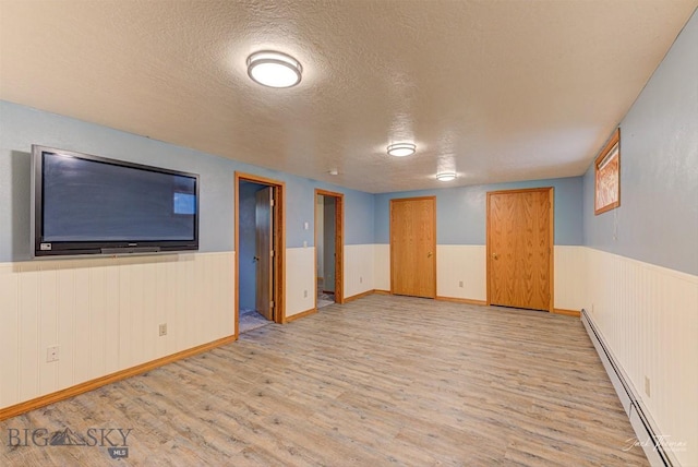 620 Higgins, Deer Lodge, MT 59722 - finished below grade area featuring a baseboard heating unit, light wood-style floors, a textured ceiling, and a wainscoted wall