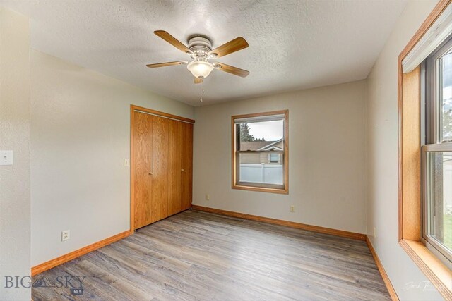 620 Higgins, Deer Lodge, MT 59722 - unfurnished bedroom with multiple windows, light wood-type flooring, a textured ceiling, and a closet