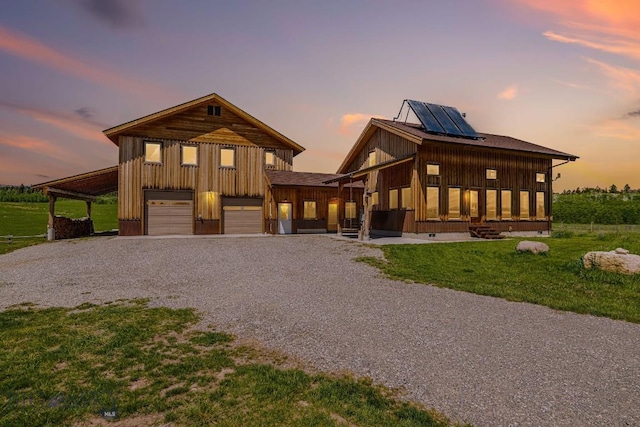 241 Aspen Loop Rd, West Yellowstone, MT 59758 - view of front of house with driveway, board and batten siding, solar panels, and a lawn