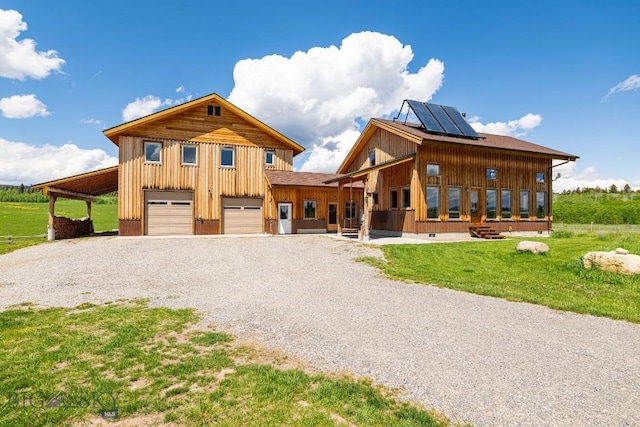 241 Aspen Loop Rd, West Yellowstone, MT 59758 - view of front facade featuring gravel driveway, roof mounted solar panels, board and batten siding, and a front lawn