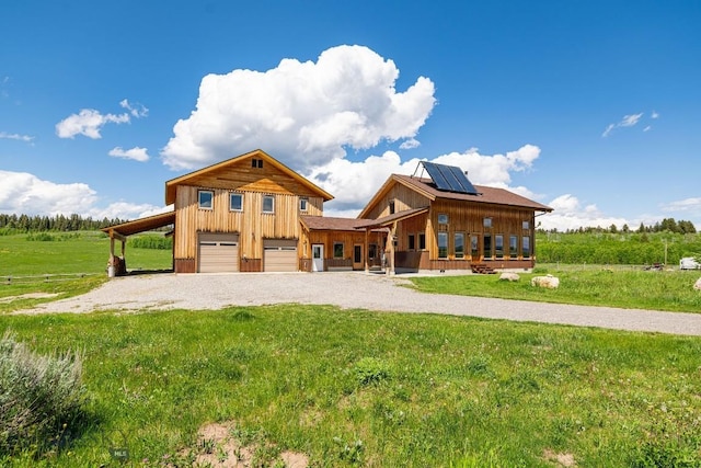 241 Aspen Loop Rd, West Yellowstone, MT 59758 - view of front of home with gravel driveway, roof mounted solar panels, a front lawn, and board and batten siding