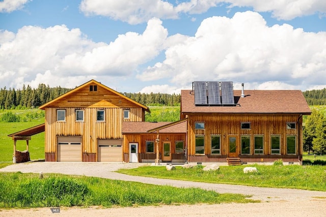241 Aspen Loop Rd, West Yellowstone, MT 59758 - view of front of home featuring board and batten siding, dirt driveway, solar panels, and a shingled roof