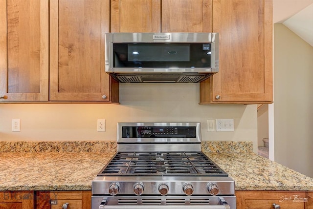 960 Strawberry, Helena, MT 59601 - kitchen featuring stainless steel appliances, brown cabinets, light stone counters, and lofted ceiling