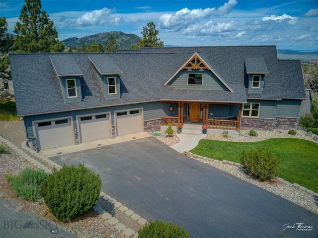 960 Strawberry, Helena, MT 59601 - view of front facade featuring stone siding, a porch, a mountain view, a shingled roof, and driveway