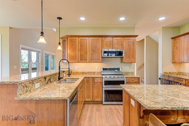 960 Strawberry, Helena, MT 59601 - kitchen with appliances with stainless steel finishes, a peninsula, light stone countertops, light wood-style floors, and decorative light fixtures