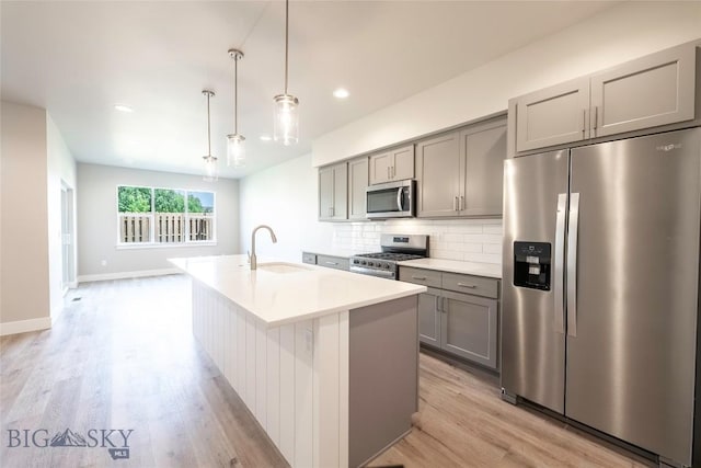 488 Meriwether Ave, Bozeman, MT 59718 - kitchen with stainless steel appliances, gray cabinetry, light wood-style flooring, tasteful backsplash, and a center island with sink