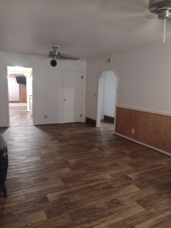 600 C St, Townsend, MT 59644 - spare room featuring a ceiling fan, dark wood-style flooring, arched walkways, wainscoting, and wood walls