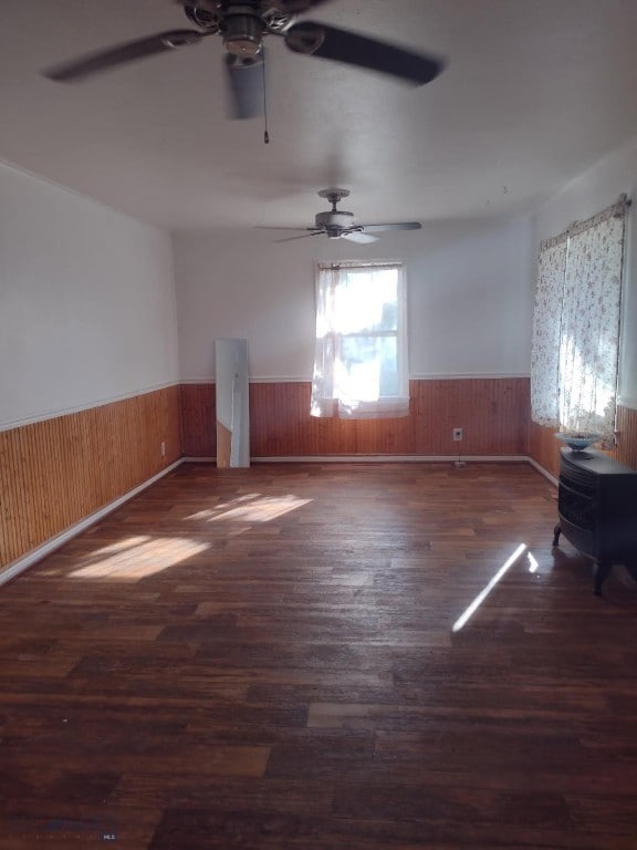600 C St, Townsend, MT 59644 - empty room with wainscoting, ceiling fan, wood finished floors, wood walls, and a wood stove