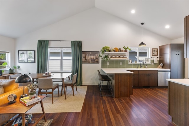25 W Dooley Ln, Belgrade, MT 59714 - kitchen featuring stainless steel dishwasher, high vaulted ceiling, a peninsula, light countertops, and a breakfast bar