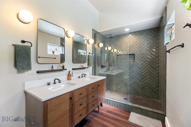 25 W Dooley Ln, Belgrade, MT 59714 - bathroom featuring double vanity, a tile shower, vaulted ceiling, and wood finished floors