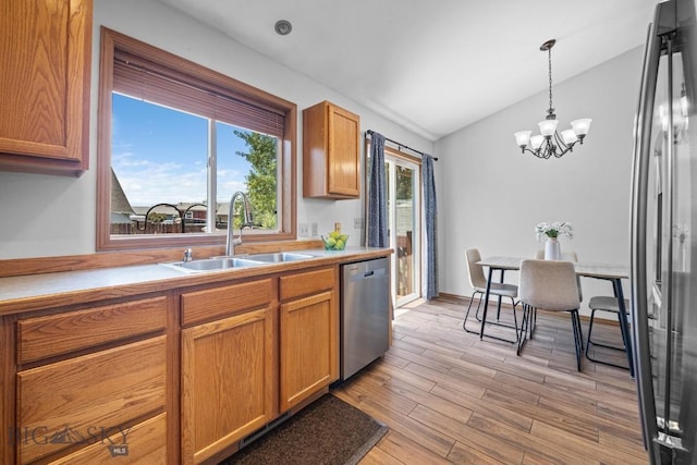 704 Mayfair Dr, Belgrade, MT 59714 - kitchen featuring appliances with stainless steel finishes, lofted ceiling, brown cabinetry, a chandelier, and light wood finished floors