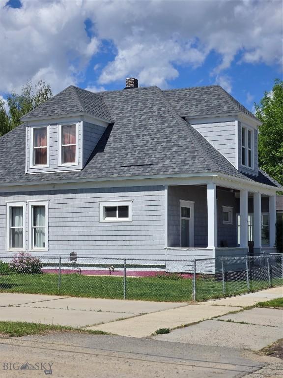415 W 6th St, Anaconda, MT 59711 - view of front of home with covered porch, a chimney, a shingled roof, and a fenced front yard