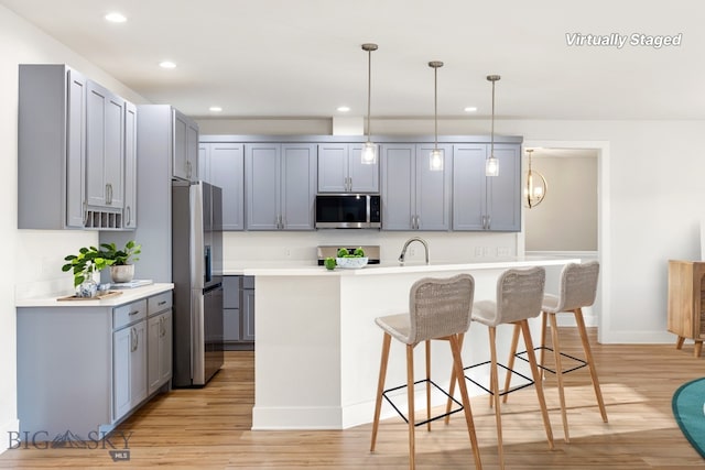 20 Hollow Top Trl, Three Forks, MT 59752 - kitchen featuring appliances with stainless steel finishes, a breakfast bar area, light wood-style flooring, gray cabinets, and recessed lighting