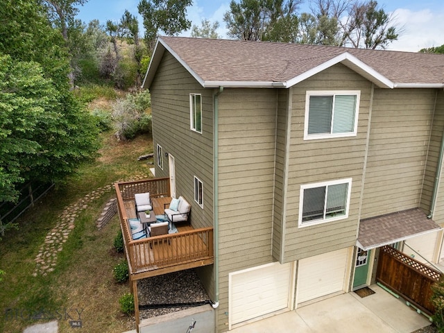 1203 Wineglass Ct Unit B, Livingston, MT 59047 - rear view of house with a garage, a deck, roof with shingles, concrete driveway, and outdoor lounge area