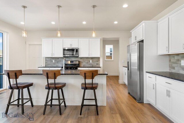 1606 Wyatt Earp Ct, Belgrade, MT 59714 - kitchen featuring appliances with stainless steel finishes, decorative backsplash, white cabinetry, a kitchen island with sink, and recessed lighting